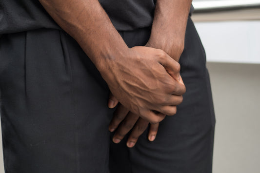 Mann mit Prostataentzündung hält sich Intimbereich mit seinen Händen zu. 