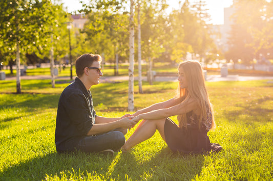 Junges Paar sitzt an einem sonnigen Tag auf der Wiese. Das Bild dient der Sensibilisierung junger Paare für sexuell übertragbare Krankheiten wie Syphilis.